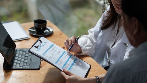 Woman showing a health insurance form and pointing thing out with a pen to a man